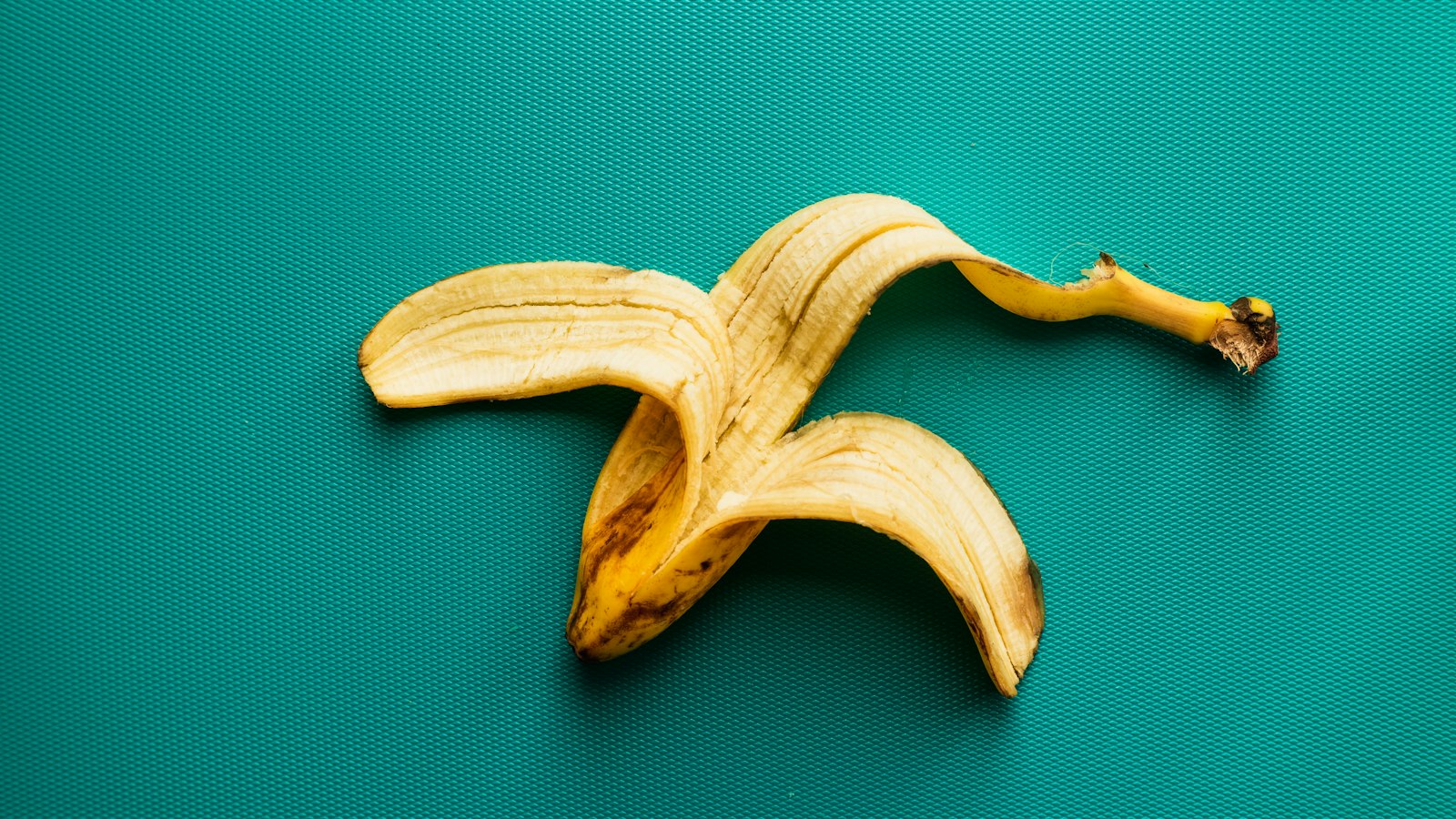 Bananenschalen kompostieren: Worauf es wirklich ankommt Natur Allianz Leere Bananenschale auf türkisfarbenem Untergrund
